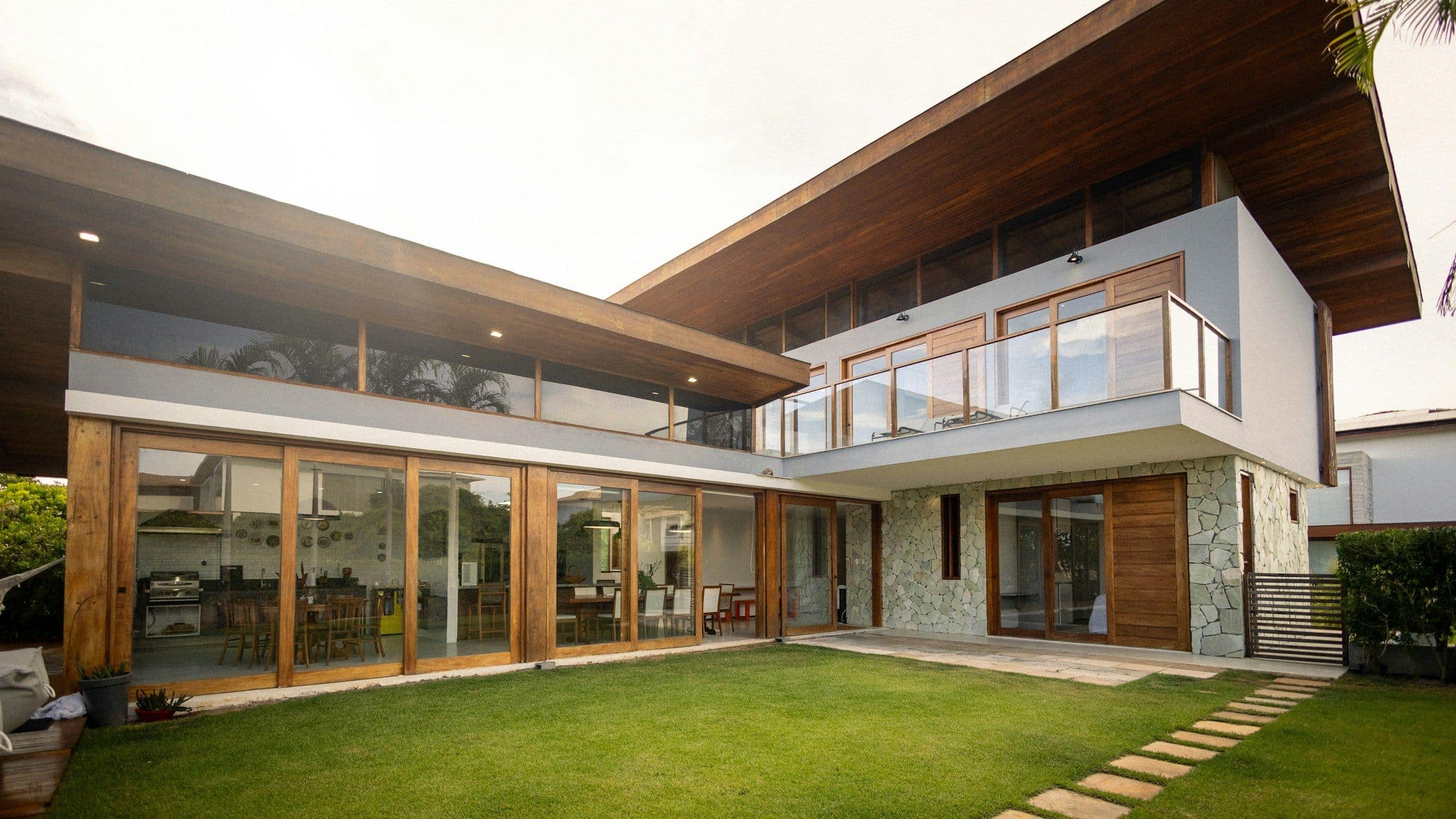 A modern two-storey home with timber and glass facing a green lawn
